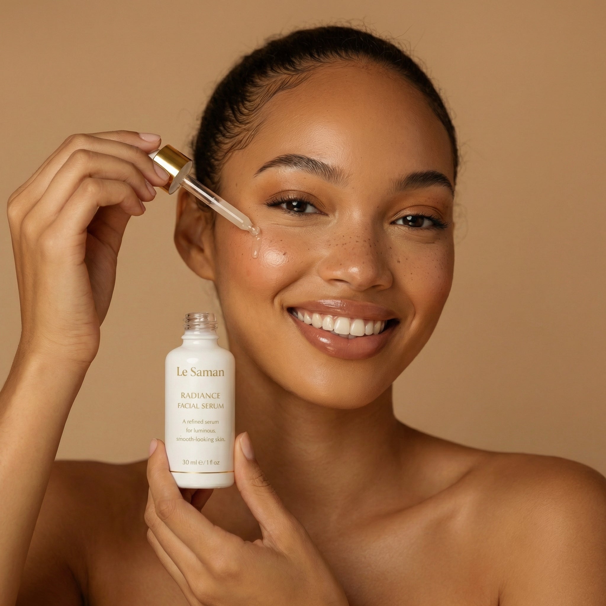 Woman holding a dropper and bottle of Le Saman skincare product against a beige background